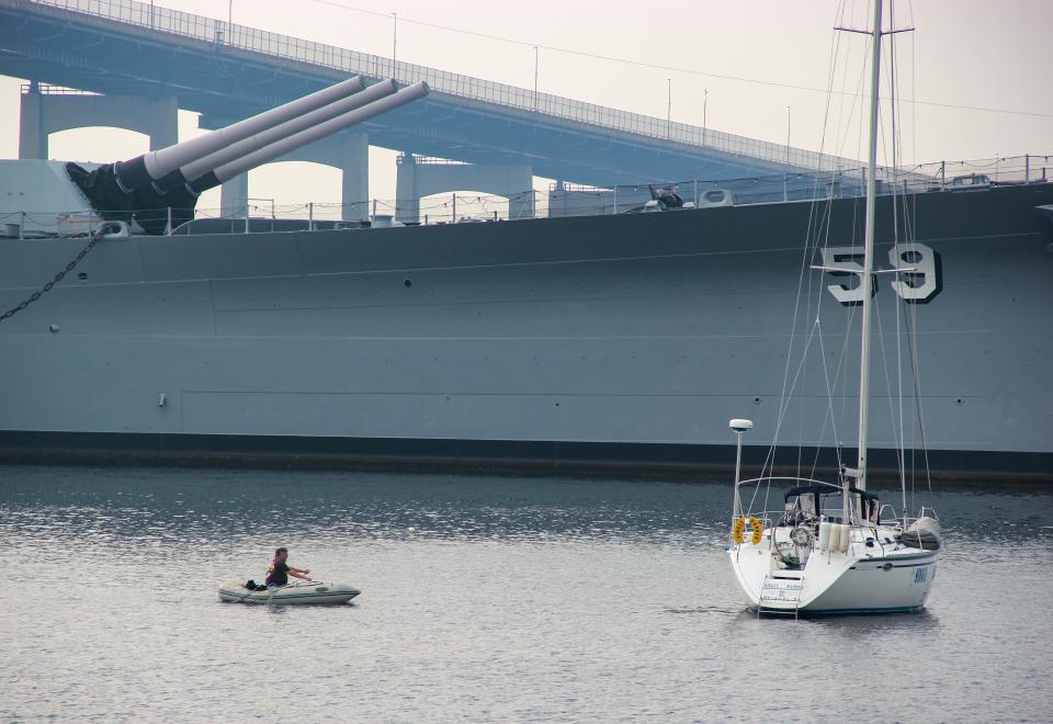 A boater paddles up to a boat moored in Battleship Cove, on Tuesday, June 6, 2023.