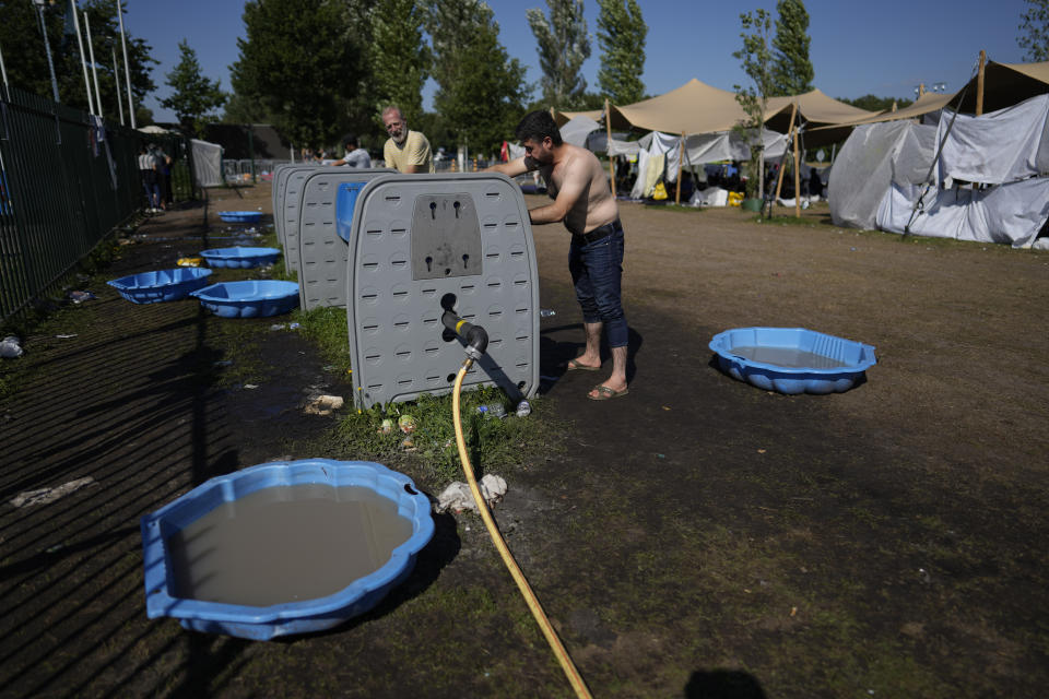 Children's pools serve as bathing facility as hundreds of migrants seek shelter outside an overcrowded asylum seekers center in Ter Apel, northern Netherlands, Thursday, Aug. 25, 2022. (AP Photo/Peter Dejong)