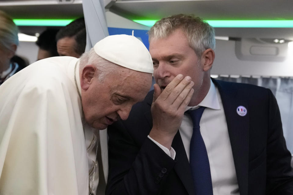 Pope Francis shares a word with director of the Holy See press office Matteo Bruni during a press conference on board an airplane on his flight back from Marseille to Rome, Saturday, Sept. 23, 2023. Francis just ended a two-day visit to Marseille where he joined Catholic bishops from the Mediterranean region on discussions largely focused on migration. (AP Photo/Alessandra Tarantino, Pool)