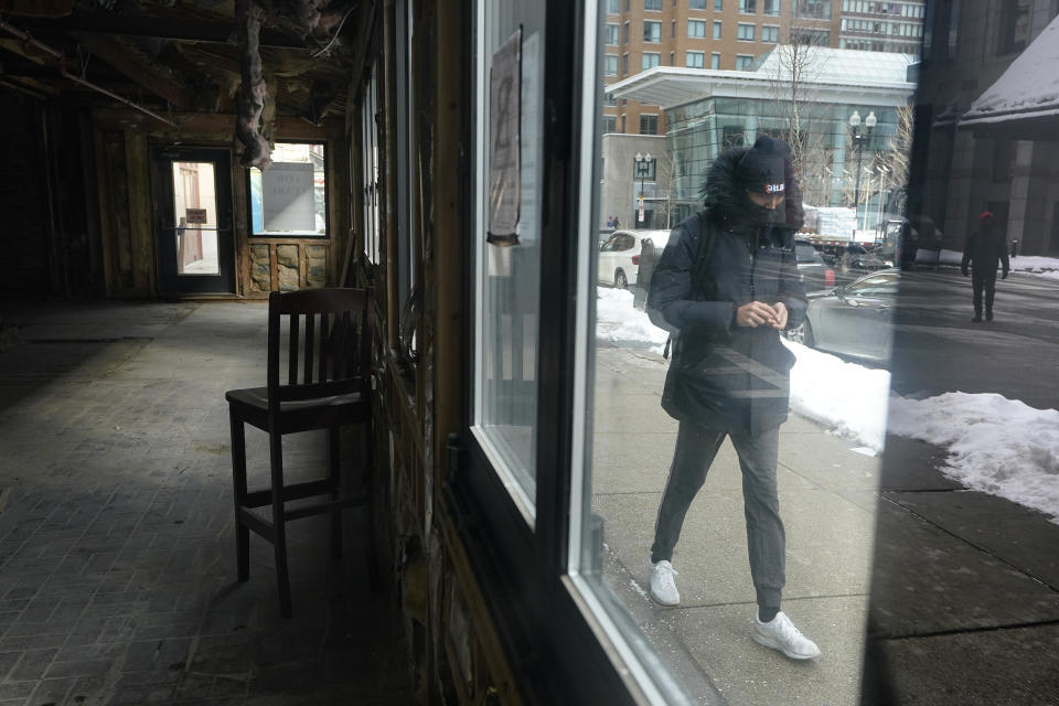 FILE - In this Feb. 10, 2021, file photo, a passerby walks past an empty building that was formerly a restaurant in Boston. Massive fraud in the nation's unemployment system is raising alarms even as President Joe Biden and Congress prepare to pour hundreds of billions more into expanded benefits for those left jobless by the coronavirus pandemic. (AP Photo/Steven Senne, File)