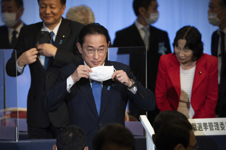 FILE - In this Sept. 29, 2021, file photo, Japan's former Foreign Minister Fumio Kishida, center, puts on his face mask as he leaves the stage after winning the Liberal Democrat Party leadership election in Tokyo. Kishida, the man soon to become Japan's next prime minister says he believes raising incomes is the only way to get the world's third-largest economy growing again.(Carl Court/Pool Photo via AP, File)