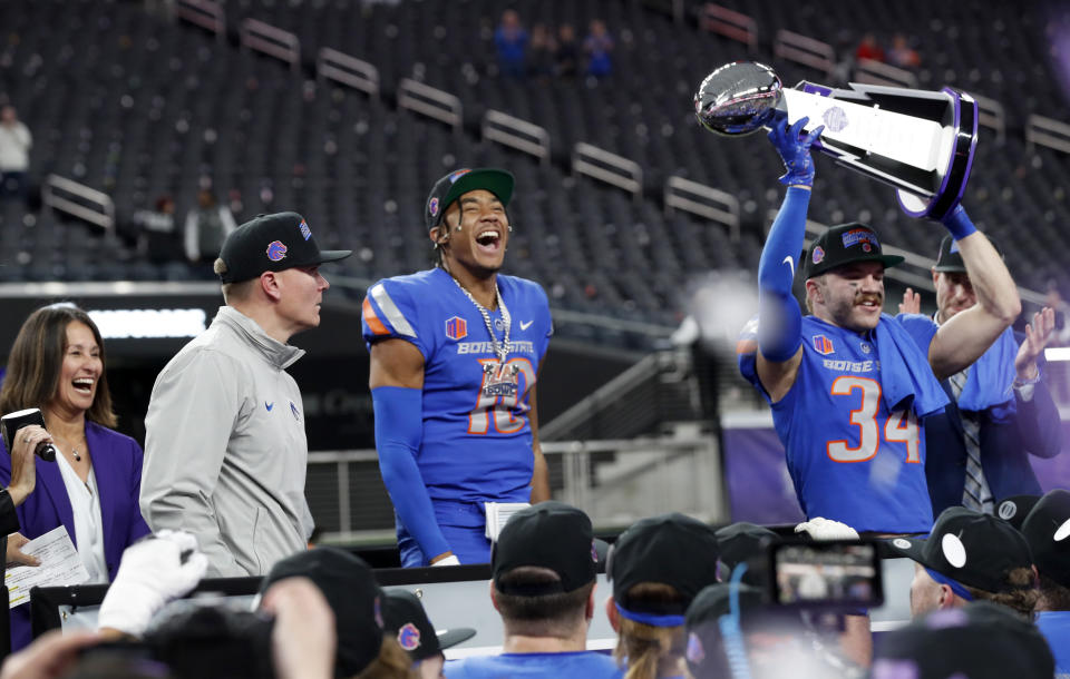 Boise State interim head coach Spencer Danielson, left, quarterback Taylen Green (10) and safety Alexander Teubner (34) celebrate with the trophy after of the Mountain West championship NCAA college football game against UNLV, Saturday, Dec. 2, 2023, in Las Vegas. (Steve Marcus/Las Vegas Sun via AP)