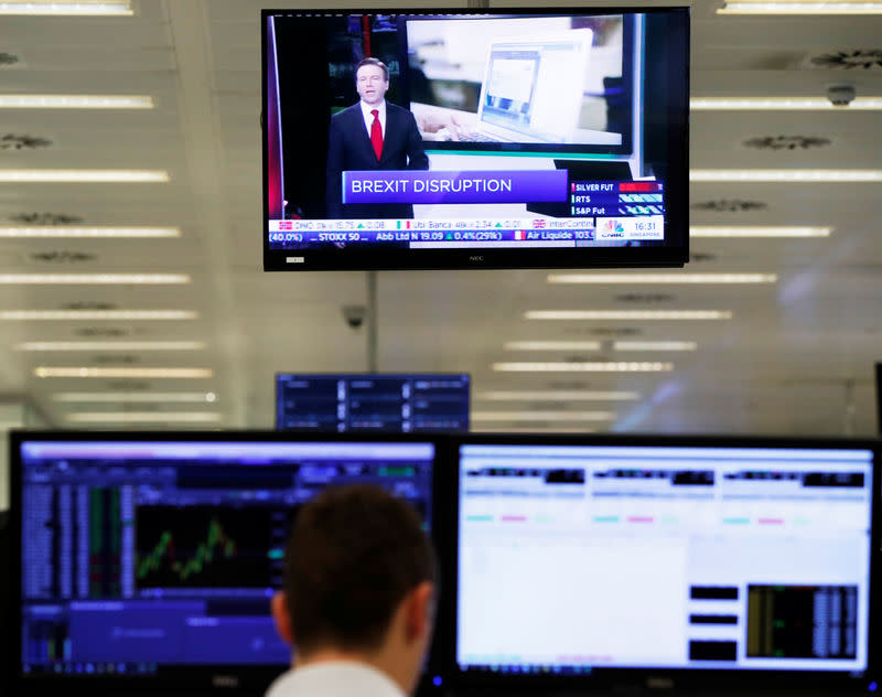 A trader watches a television screen as he works at his desk whilst screens show market data at CMC Markets in London, Britain, January 16, 2019. REUTERS/John Sibley