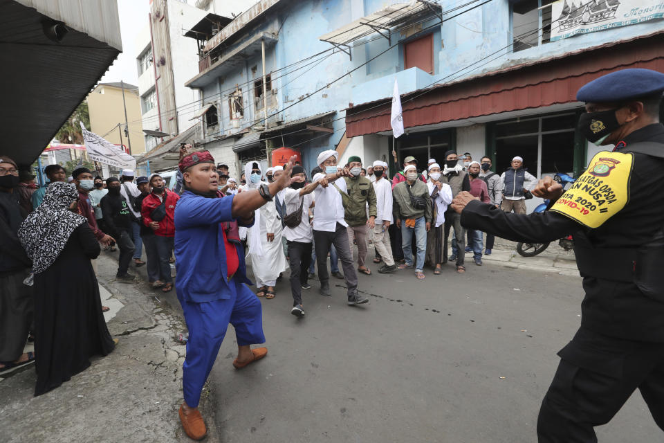Supporters of Rizieq Shihab, leader of the Islam Defenders Front, confront a police officers during a rally in Jakarta, Indonesia, Friday, Dec. 18, 2020. Hundreds of protesters marched in Indonesia's capital on Friday to demand the release of the firebrand cleric who is in police custody on accusation of inciting people to breach pandemic restrictions and ignoring measures to curb the spread of COVID-19 by holding several events, and justice for his six followers who were killed in a shootout with the police. (AP Photo/Tatan Syuflana)