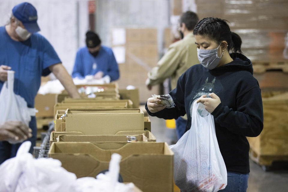 Volunteer Ana Willis fills a bag with food items for the backpack program at Feeding America food bank in Elizabethtown, Ky., Monday, Jan. 17, 2022. Food banks across the country are experiencing a critical shortage of volunteers as the omicron variant frightens people away from group activities. (AP Photo/Michael Clubb)