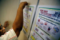 A resident volunteer puts up posters in a lift of a public housing estate in a Zika cluster in Singapore September 2, 2016. REUTERS/Edgar Su