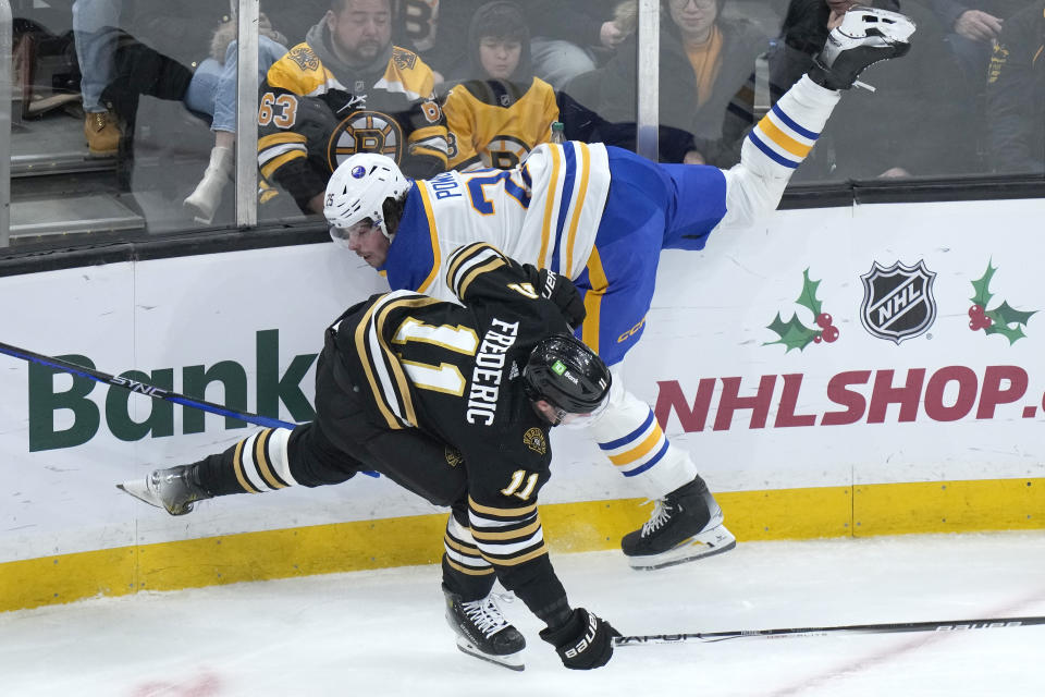 Boston Bruins center Trent Frederic (11) and Buffalo Sabres defenseman Owen Power (25) slam into the boards after colliding during the second period of an NHL hockey game Thursday, Dec. 7, 2023, in Boston. (AP Photo/Steven Senne)