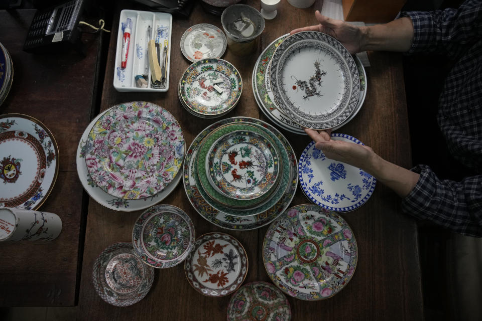 Joseph Tso, owner of Yuet Tung China Works, Hong Kong's porcelain factory, holds a plate with dragon print in Hong Kong, Wednesday, June 8, 2022. Step into Yuet Tung China Works, Hong Kong’s last remaining hand-painted porcelain factory, and you find yourself surrounded by stacks of dinnerware, each piece painstakingly decorated by hand with vibrant motifs of flowers, fruits and animals. (AP Photo/Kin Cheung)