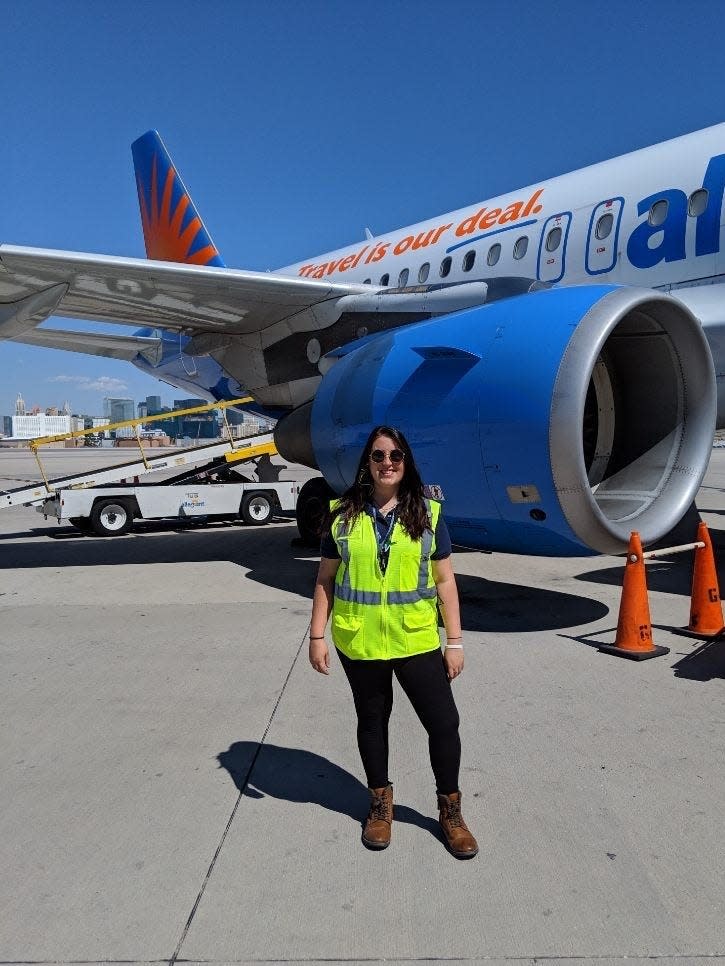 Taylor Rains stands in front of an Allegiant Air plane.