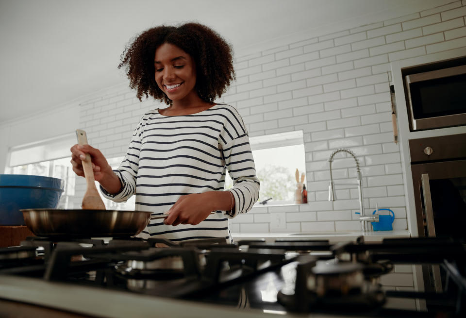 A woman cooking in the kitchen and smiling.