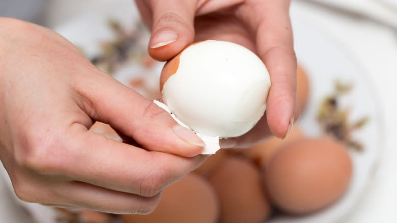 Hands peeling eggs