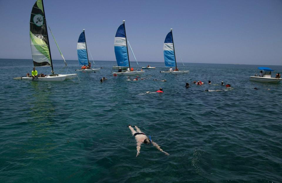 In this May 12, 2019 photo, tourists snorkel in the Caribbean, off a beach in Varadero, Cuba. As most of Cuba’s economy stagnates or declines, the country has launched a full-scale effort to turn virtually the only bright spot, tourism, into an engine that can drag the rest of the communist island through its worst economic crisis in two decades. (AP Photo/Ismael Francisco)