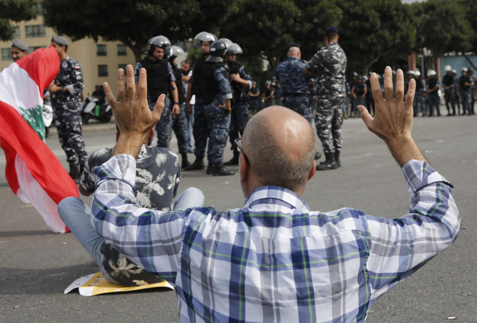 An anti-government protester blocking a main highway, raises up his hands after police prepare to remove them and open the road in Beirut, Lebanon, Saturday, Oct. 26, 2019. The removal of the roadblocks on Saturday comes on the tenth day of protests in which protesters have called for civil disobedience until the government steps down. (AP Photo/Hussein Malla)