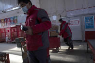 In this Tuesday, Feb. 18, 2020, photo, delivery workers for Chinese e-commerce giant JD.com prepare for the morning round of deliveries from a distribution center in Beijing, China. JD and rivals including Pinduoduo, Miss Fresh and Alibaba Group's Hema are scrambling to fill a boom in orders while protecting their employees. E-commerce is one of the few industries to thrive after anti-virus controls starting in late January closed factories, restaurants, cinemas, offices and shops nationwide and extinguished auto and real estate sales. (AP Photo/Ng Han Guan)