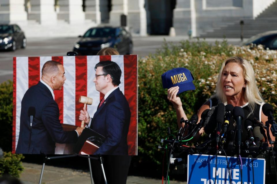 Georgia GOP Rep. Marjorie Taylor Greene holds up a hat that says “MUGA” or “Make Ukraine Great Again” as she speaks at a news conference alongside Rep. Thomas Massie (R-KY) at the Capitol on 1 May 2024 in Washington, DC (Getty Images)