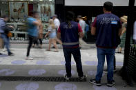 Tax agency employees stand in the middle of a pedestrian street to act as a deterrent to illegal currency traders, in Buenos Aires, Argentina, Tuesday, Nov. 21, 2023. (AP Photo/Natacha Pisarenko)