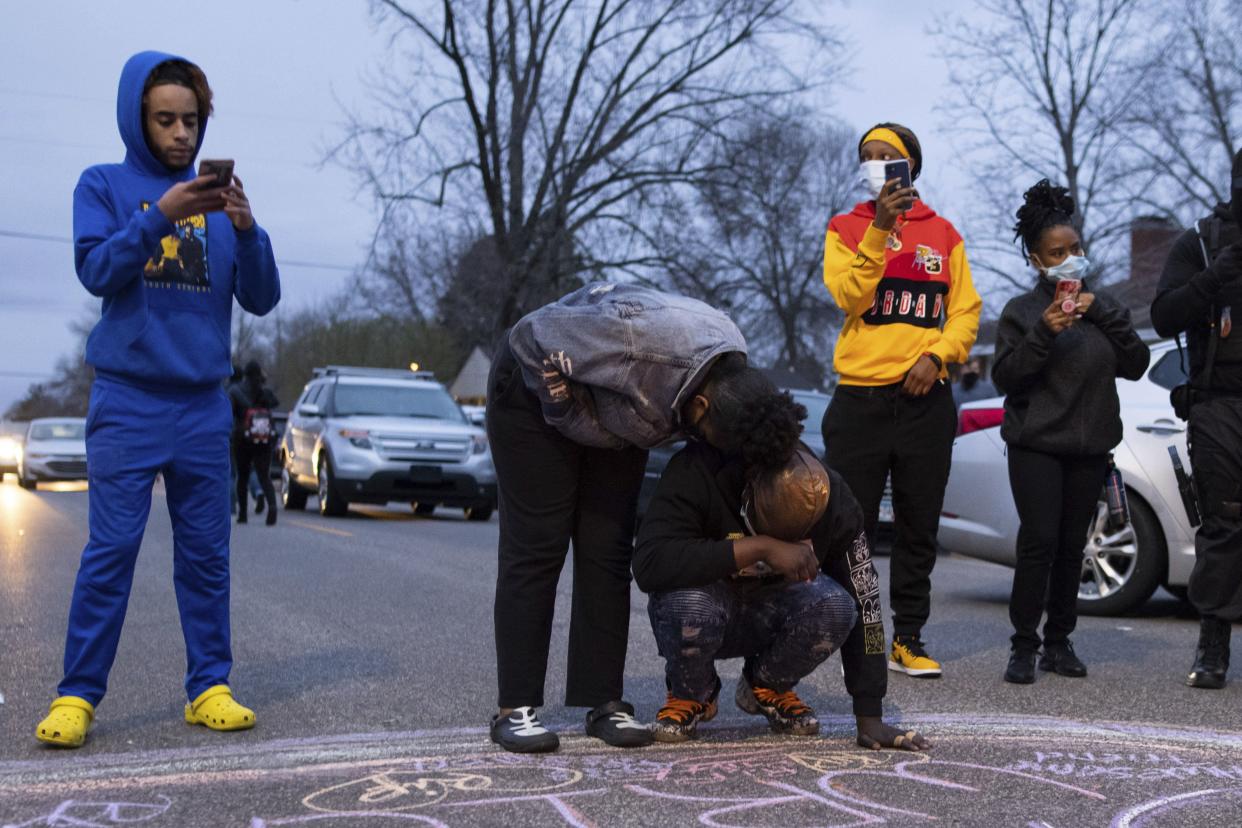 People stand and react to a shooting, Sunday, April 11, 2021, in Brooklyn Center, Minn. The family of Daunte Wright, 20, told a crowd that he was shot by police Sunday before getting back into his car and driving away, then crashing the vehicle several blocks away. The family said Wright was later pronounced dead.