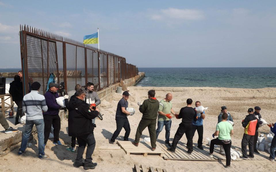 Local residents carry bags filled with sand as they build a barricade for a check-point in Odesa on March 25, 2022, amid the Russian invasion of Ukraine.  - Oleksandr Gimanov/AFP