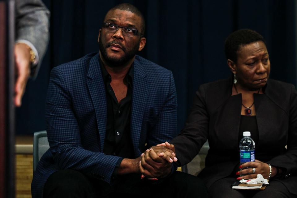 Media mogul Tyler Perry, left, holds the hand of Marcia Roberts, the mother of Terrance Williams.