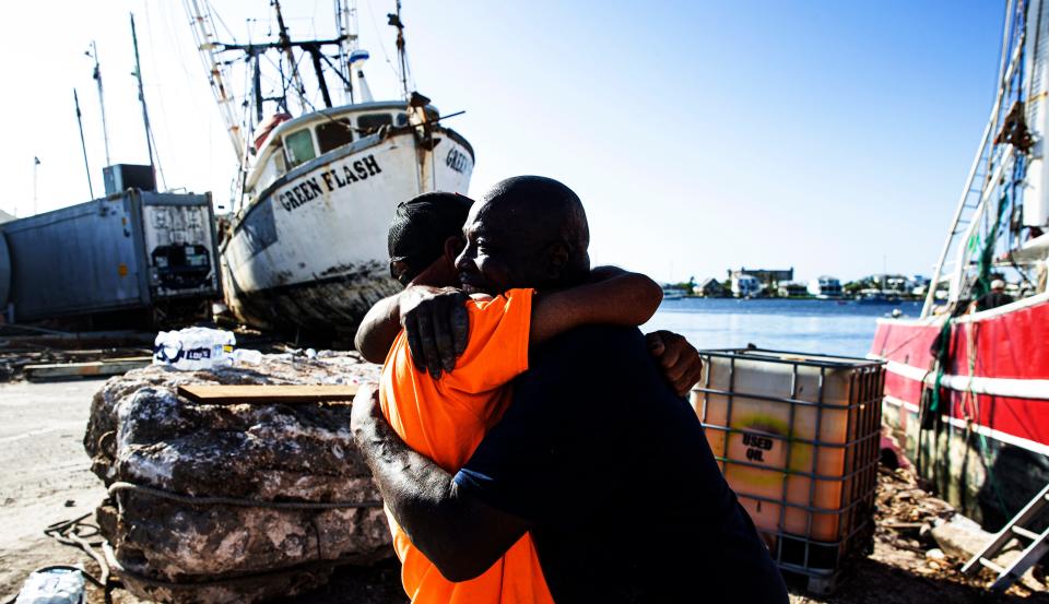 Kenny Washington, right, the first mate on the shrimp boat the Malolo, greets Scott Wilson at the shrimp docks on Nov. 7, 2022. The Malolo was coming in with the first catch of shrimp since Hurricane Ian decimated the fleet. It was one of only three boats that weren't damaged, destroyed or left on land after the Category 4 storm. Washington had been out shrimping for almost a month. Washington survived the hurricane on the Green Flash, behind him, after having to jump off the Perseverance, a boat he was captaining.