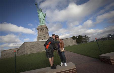 A couple take a photo of themselves in front of the Statue of Liberty as people arrive on the first tour boat to go to Liberty Island since it was shuttered in almost two weeks ago in New York, October 13, 2013. REUTERS/Carlo Allegri