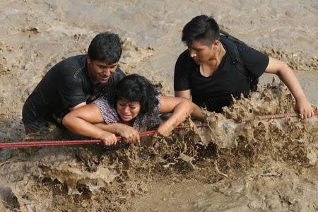 Gente cruza una calle inundada en el barrio de Huachipa en Lima. 17 de marzo de 2017. La mitad de Perú se encuentra en estado de emergencia por el desborde de ríos y aludes de lodo y piedras que han destruido carreteras, puentes y arrastrado personas y animales, en un inesperado fenómeno climático de "El Niño Costero" que se prolongaría hasta abril. REUTERS/Guadalupe Pardo