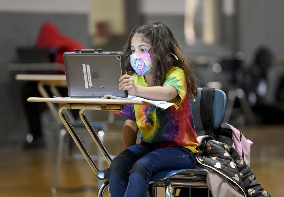 A 7-year-old does her school work using an iPad.