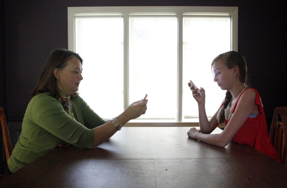 In this Thursday, May 24, 2012 photo, Anna Schiferl, right, and her mother, Joanna, pose for a photograph holding their cell phones in the dining room of their LaGrange, Ill. home. Statistics from the Pew Internet & American Life Project show that, these days, many people with cell phones prefer texting over a phone call. It’s not always young people, though the data indicates that the younger you are, the more likely you are to prefer texting. But many experts say the most successful communicators will, of course, have the ability to do both talk or text, and know the most appropriate times to use those skills. (AP Photo/Charles Rex Arbogast)