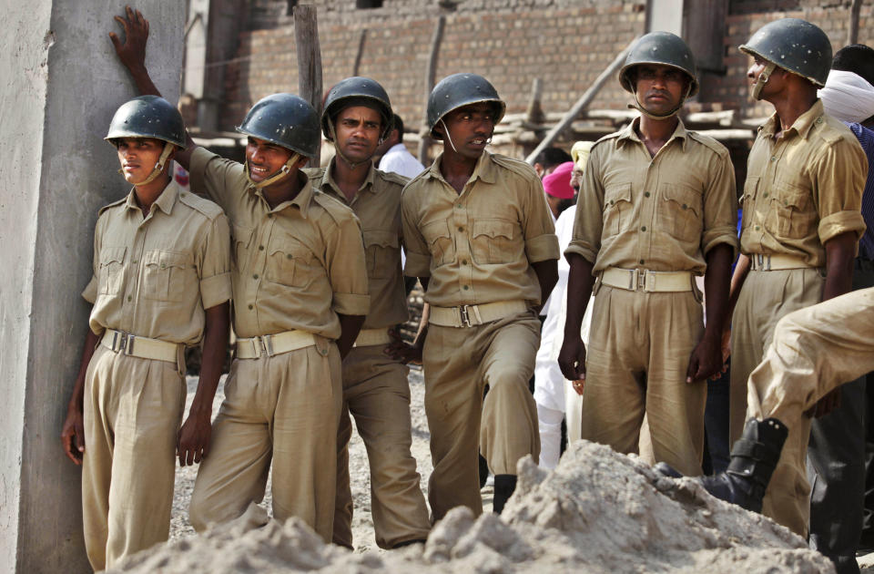 Indian paramilitary troopers stand near the site of a building collapse in Jalandhar, India, Monday, April 16, 2012. Several people are feared to be trapped after a three-story building of a factory collapsed after a blast in the factory's boiler, according to local reports. (AP Photo/Altaf Qadri)