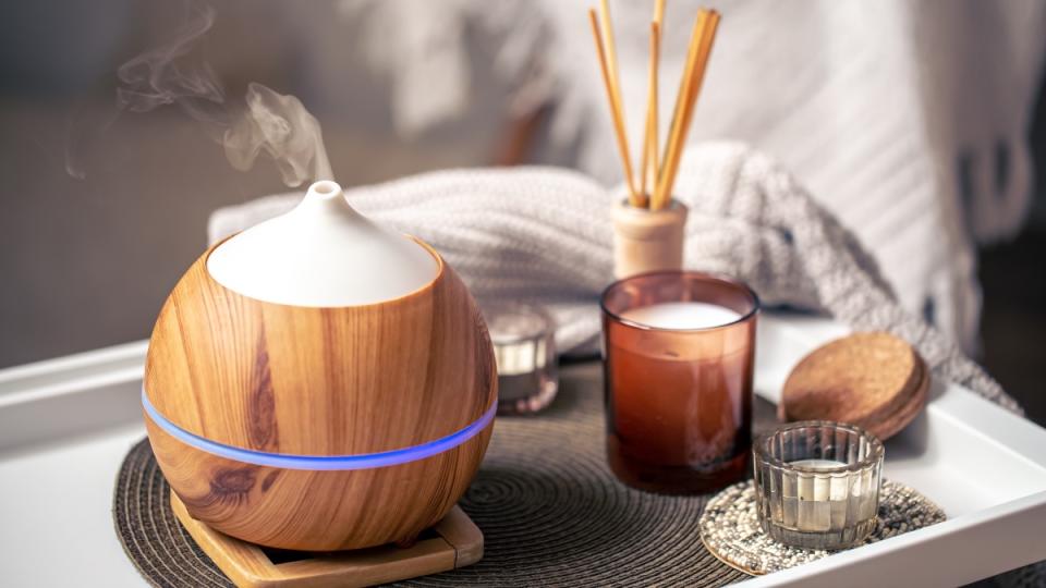 An aromatherapy diffuser for essential oils, which can ease congestion, beside candles