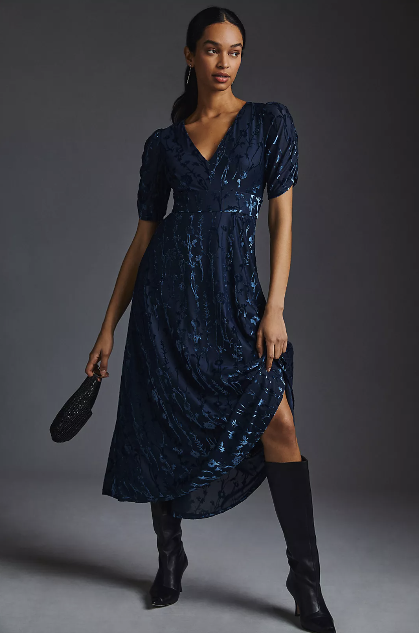 woman wearing black knee high boots and dark navy blue Hutch Puff-Sleeve Velvet Dress (Photo via Anthropologie)