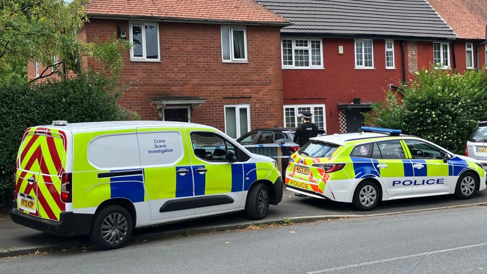 A crime scene investigation van and police vehicle outside a cordoned off house, which is being guarded by a police constable