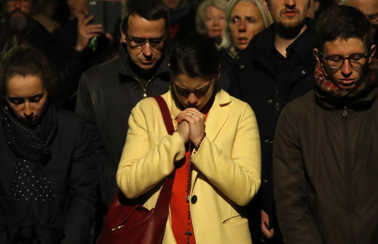 People pray as Notre Dame Cathedral burns.