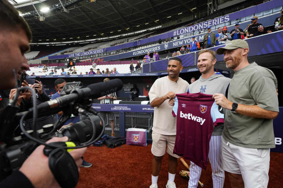 Pete Alonso, de los Mets de Nueva York, posa para una foto con los exfutbolistas del West Ham Anton Ferdinand y James Collins, durante un día de entrenamiento en el estadio de Londres, el viernes 7 de junio de 2024. Los Mets jugarán contra los Filis de Filadelfia en Londres el 8 y 9 de junio. (AP Foto/Kirsty Wigglesworth)