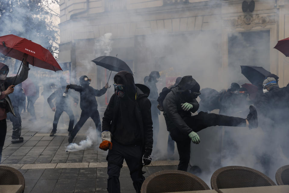 Protesters clashes with polices officers as they stand in a cloud of teargas during a demonstration in Nantes, western France, Saturday, March 11, 2023. Opponents of President Emmanuel Macron's hotly contested plan to raise the retirement age from 62 to 64 were taking to the streets of France on Saturday for the second time this week in what union's hope will be a new show of force meant to push the government to back down. (AP Photo/Jeremias Gonzalez)