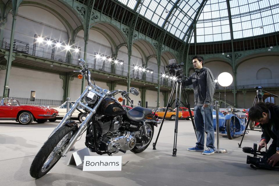 Cameramen shoot the 1,585 cc Harley Davidson Dyna Super Glide, donated to Pope Francis last year and signed by him on its tank, which is displayed as part of Bonham's Les Grandes Marques du Monde vintage and classic cars sale at the Grand Palais in Paris, February 5, 2014. Signed "Francesco" on its tank, the motorcycle, to be auctioned for charity in Paris on February 6, has an unusual owner - Pope Francis. The Pope will sell his Harley Davidson to raise funds for Caritas Roma, a charity working on behalf of the church, auctioneer Bonhams said. REUTERS/Benoit Tessier (FRANCE - Tags: TRANSPORT SOCIETY RELIGION MEDIA)