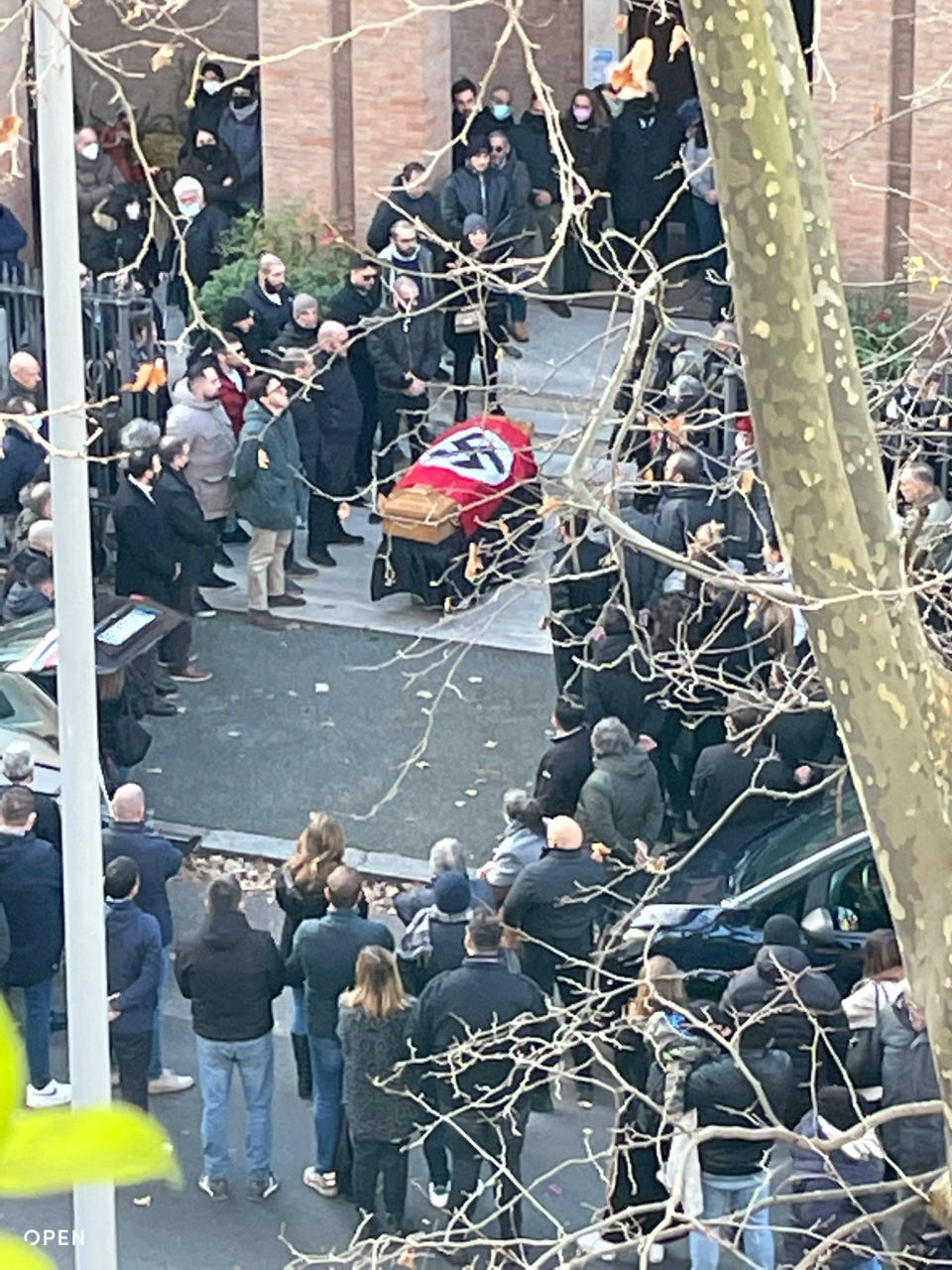 A picture made available by the Italian online news portal Open, showing people gathered around a swastika-covered casket outside the St. Lucia church, in Rome, Monday, Jan. 10, 2022. The Catholic Church in Rome on Tuesday, Jan. 11, 2022, strongly condemned as "offensive and unacceptable" a funeral procession outside a church in which the casket was draped in a Nazi flag and mourners gave the fascist salute. (Open Via AP)