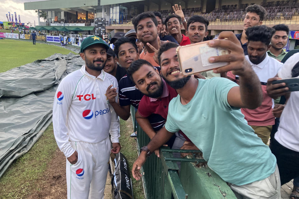 Pakistan's Saud Shakeel poses for selfies with Sri Lankan cricket fans at the end of day three of the first cricket test match between Sri Lanka and Pakistan in Galle, Sri Lanka, on Tuesday, July 18, 2023. (AP Photo/Eranga Jayawardena)