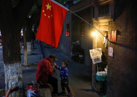 A man plays with a child underneath a Chinese national flag in a hutong alley in the old part of Beijing as the capital prepares for the 19th National Congress of the Communist Party of China, October 14, 2017. REUTERS/Thomas Peter TPX IMAGES OF THE DAY