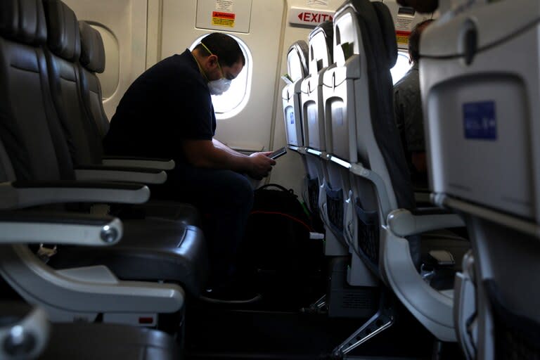 Un pasajero con barbijo mira su teléfono mientras espera a bordo de un avión de United Airlines antes de despegar del Aeropuerto Intercontinental George Bush el 11 de mayo de 2020 en Houston, Texas