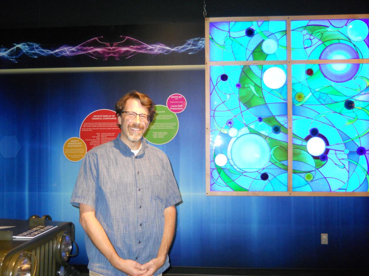 Matt Mullins, marketing director for the American Museum of Science and Energy, stands between a stained glass window and a 3-D printed Jeep exhibit at the museum.