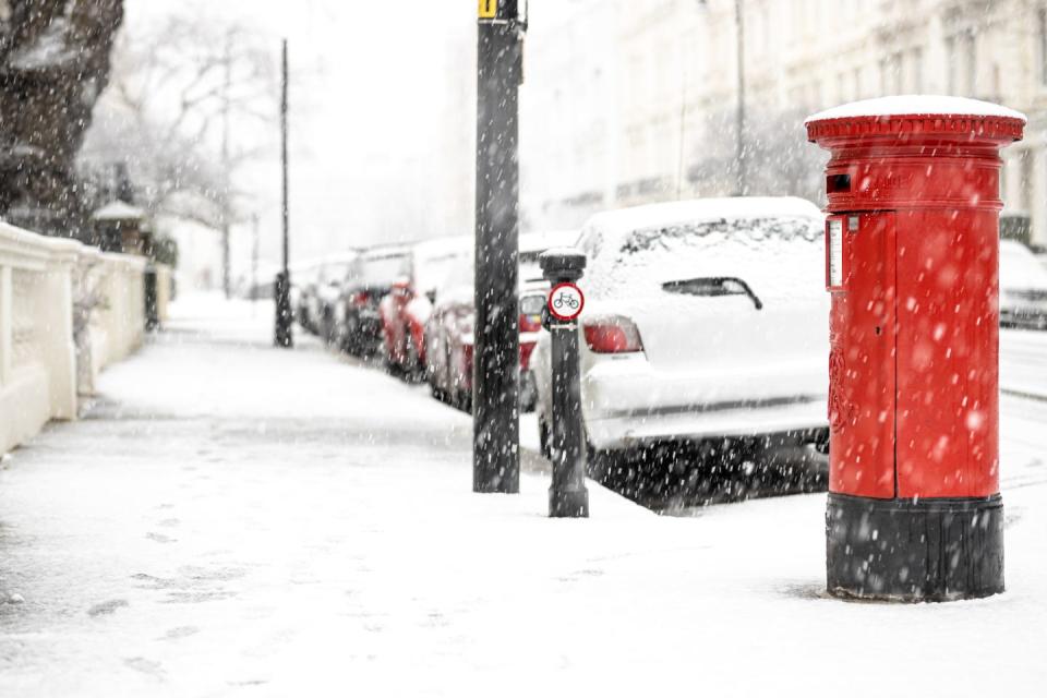 london classic red mailbox  under the falling snow, uk