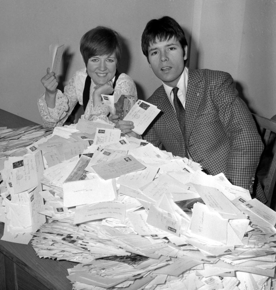 Facing a mountain of postcards are pop singers Cilla Black and Cliff Richard at BBC Television office in Shepherd's Bush, London, as they helped to count votes for Britain's song for Europe.