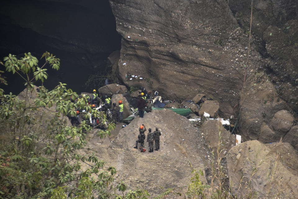 Nepalese rescue workers inspect wreckage at the site of a plane crash in Pokhara, Nepal, Monday, Jan. 16, 2023. The Yeti Airlines flight from Kathmandu that plummeted into a gorge Sunday killed at least 70 passengers out of the 72 on board. (AP Photo/Krishna Mani Baral)