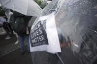 A protester, with a banner seen through her umbrella, take part in a solidarity rally for the death of George Floyd in Tokyo Sunday, June 14, 2020. Floyd died after being restrained by Minneapolis police officers on May 25. (AP Photo/Eugene Hoshiko)