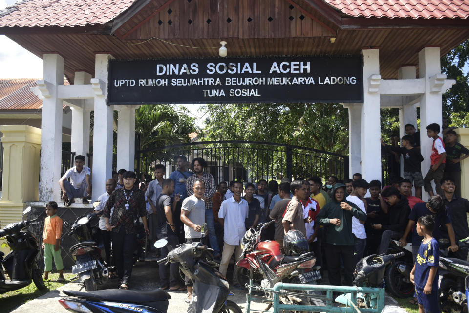 Acehnese men block the entrance gate to a temporary shelter to prevent Rohingya refugees from entering in Ladong, Aceh province, Indonesia, Monday, Dec. 11, 2023. Two boats carrying hundreds of Rohingya Muslims, including emaciated women and children, arrived on Sunday at Indonesia's northernmost province of Aceh where they faced rejection from local communities who are protesting against the increasing numbers of refugees that have entered the region over the past few weeks. (AP Photo/Reza Saifullah)