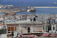 Workers repair water tanks and damaged apartments overlooking the site of the Aug. 4 explosion that hit the seaport, in Beirut, Lebanon, Thursday, Aug. 27, 2020. (AP Photo/Hussein Malla)