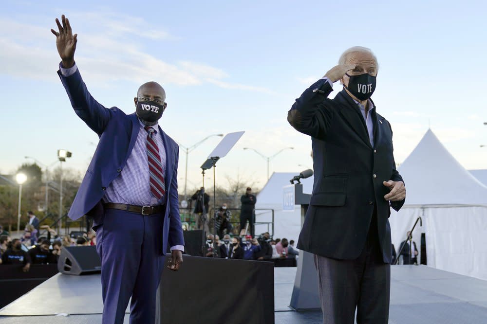 In this Monday, Jan. 4, 2021 file photo, President-elect Joe Biden, right, campaigns for Senate candidates Raphael Warnock, left, and Jon Ossoff, not pictured, in Atlanta. (AP Photo/Carolyn Kaster)