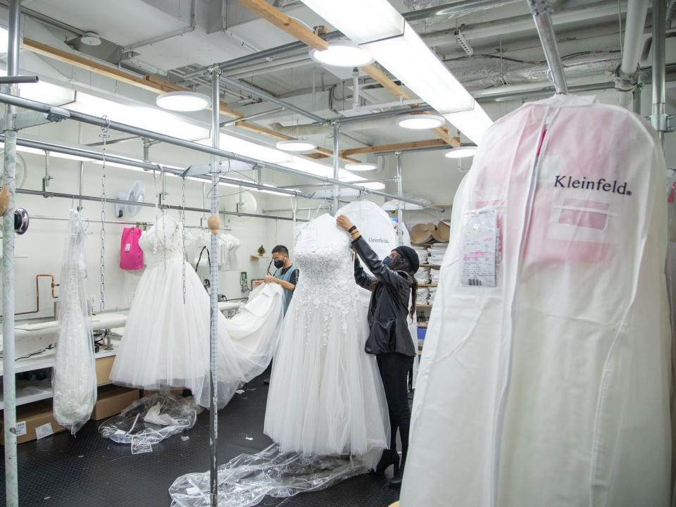 Two people adjust wedding gowns at Kleinfeld.