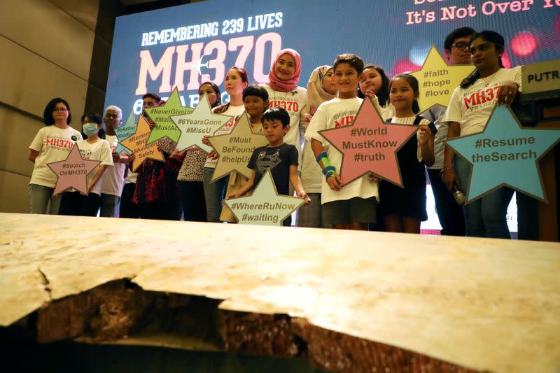 Family members of the victims pose for a group picture with a debris of the missing Malaysia Airlines flight MH370 during its sixth annual remembrance event in Putrajaya